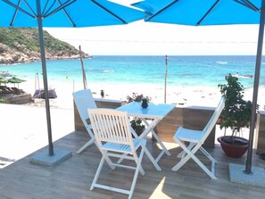 A terrace with a table and chairs, overlooking a beach and the sea. - Blue Anchor Lodge & Cafe-Binh Ba Island (Nam Cam Ranh)