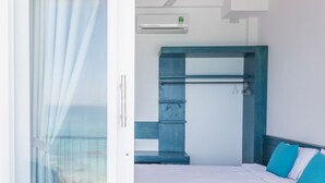 A bedroom with a bed, a built-in bench, a towel rack, and an air conditioning unit. - Blue Anchor Lodge & Cafe-Binh Ba Island (Nam Cam Ranh)