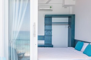 A bedroom with a bed, a built-in bench, a towel rack, and an air conditioning unit. - Blue Anchor Lodge & Cafe-Binh Ba Island (Cam Ranh)