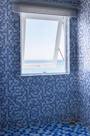 A bathroom with blue mosaic tiles, a window with a view of the sea, and a shower area. - Blue Anchor Lodge & Cafe-Binh Ba Island (Cam Ranh)