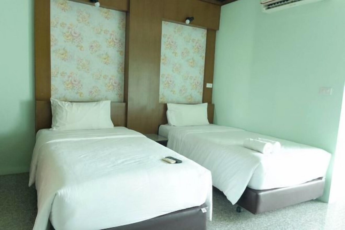 Quarto com duas camas, cada uma com travesseiro e cobertor, e uma mesa de cabeceira com telefone.