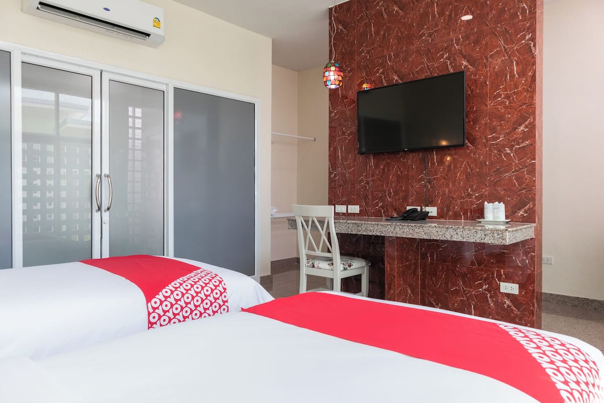 A hotel room with two beds, a desk, a TV, and a minibar.