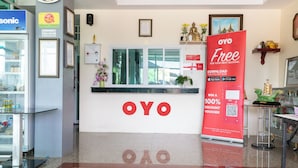 Un área de recepción con un cartel llamativo de OYO, un símbolo de WiFi y un letrero de no fumar.