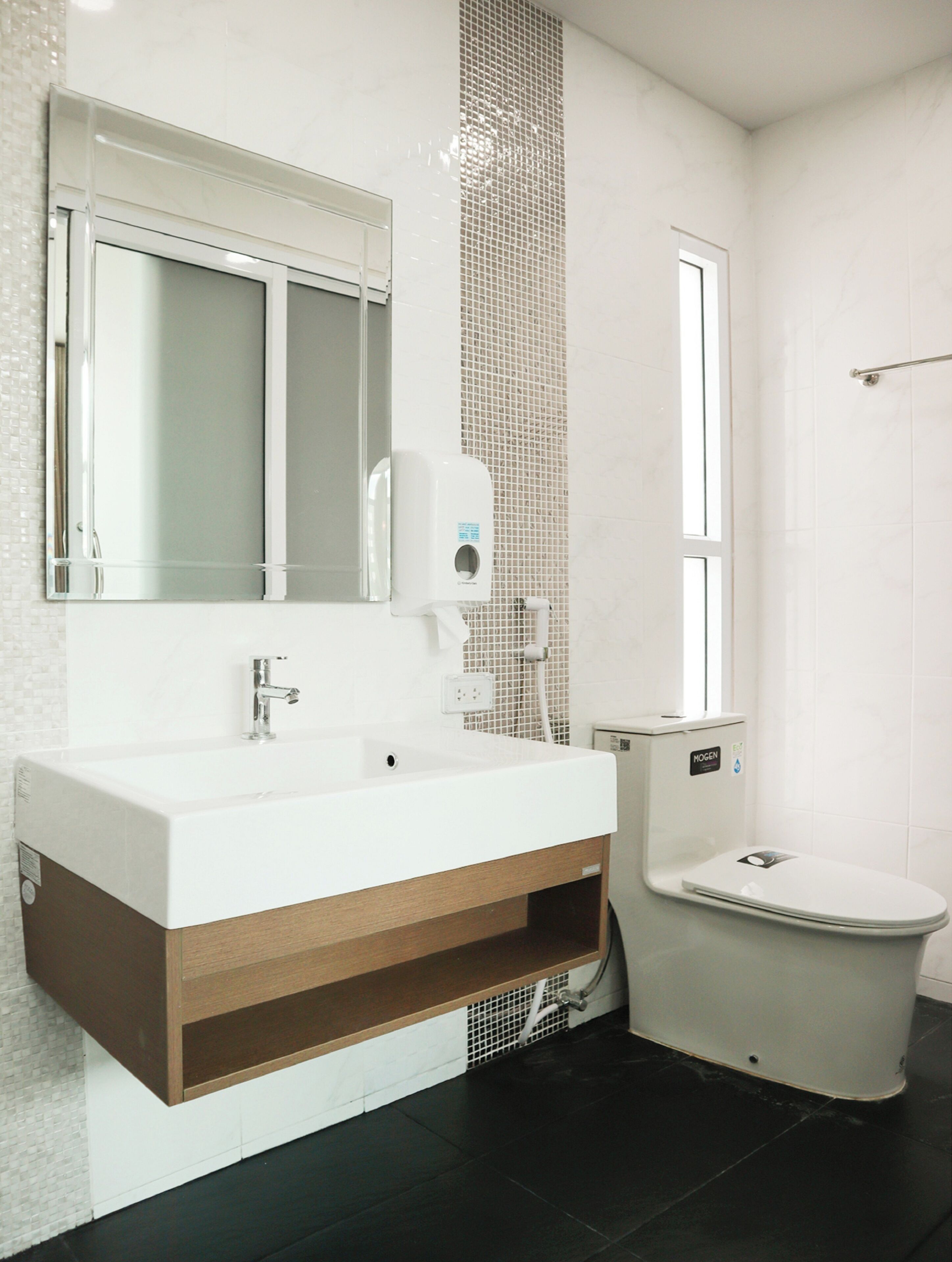 A modern bathroom with a white sink, mirror, and toilet.