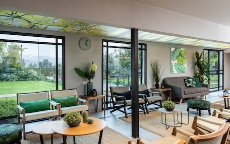 A spacious living area with large windows, a sofa, chairs, and a coffee table.