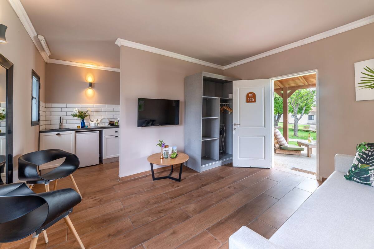 Eine moderne Küche mit weißen Schränken, einem Essbereich mit rundem Tisch und einer Sitzecke mit Sofa und Sesseln.