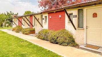A row of motel rooms with red exteriors and beige doors, numbered 235 and 236, featuring a simple, functional design with small front yards and a clear sky.