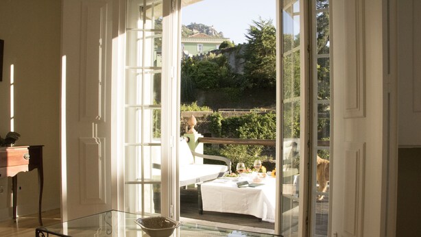 A room with a glass table, a white tablecloth, and a view of a dining area outside. - Casa Holstein Quinta de São Sebastião (Sintra)