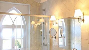 A bathroom with a glass-enclosed shower, a pedestal sink, and a large mirror.
