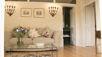 A living room with a beige sofa, a glass coffee table, and two wall-mounted candelabras.