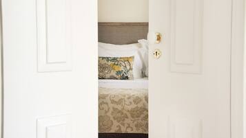 A hotel room with a bed featuring a floral-patterned bedspread and a decorative pillow.