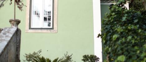 A building with a green facade, a window, and a staircase leading up.