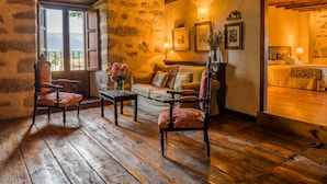 Une pièce rustique avec un plancher en bois, un mur en pierre, un lit en bois et un canapé.