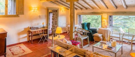 Una habitación acogedora con techo de madera, una estantería, un escritorio y una zona de estar confortable con vistas a zonas verdes.