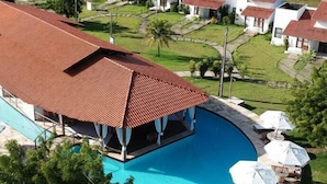 Een resort met een zwembad, meerdere villa's met rode daken en een verzorgd gazon.
