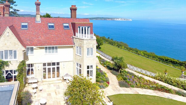 Une grande maison avec un toit rouge, une tour et une vue sur la mer.