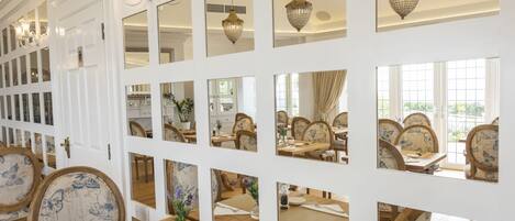 Un espace repas comprenant plusieurs tables et chaises, des murs blancs et des luminaires décoratifs.