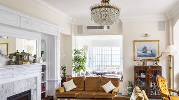 A classic living room with a fireplace, a chandelier, and a large window.