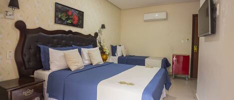 A hotel room with a large bed, a bedside table, a TV, and a red cabinet.