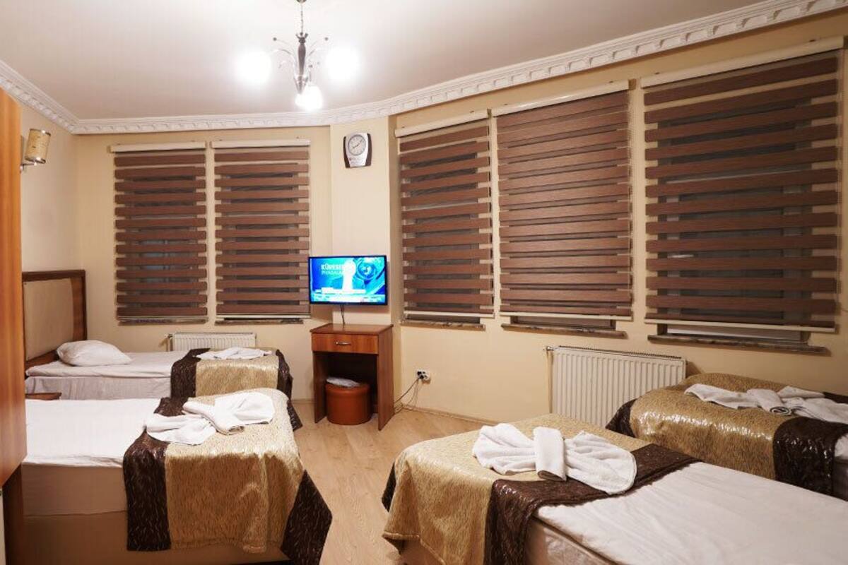A hotel room with two beds, a television, and a wooden wardrobe.