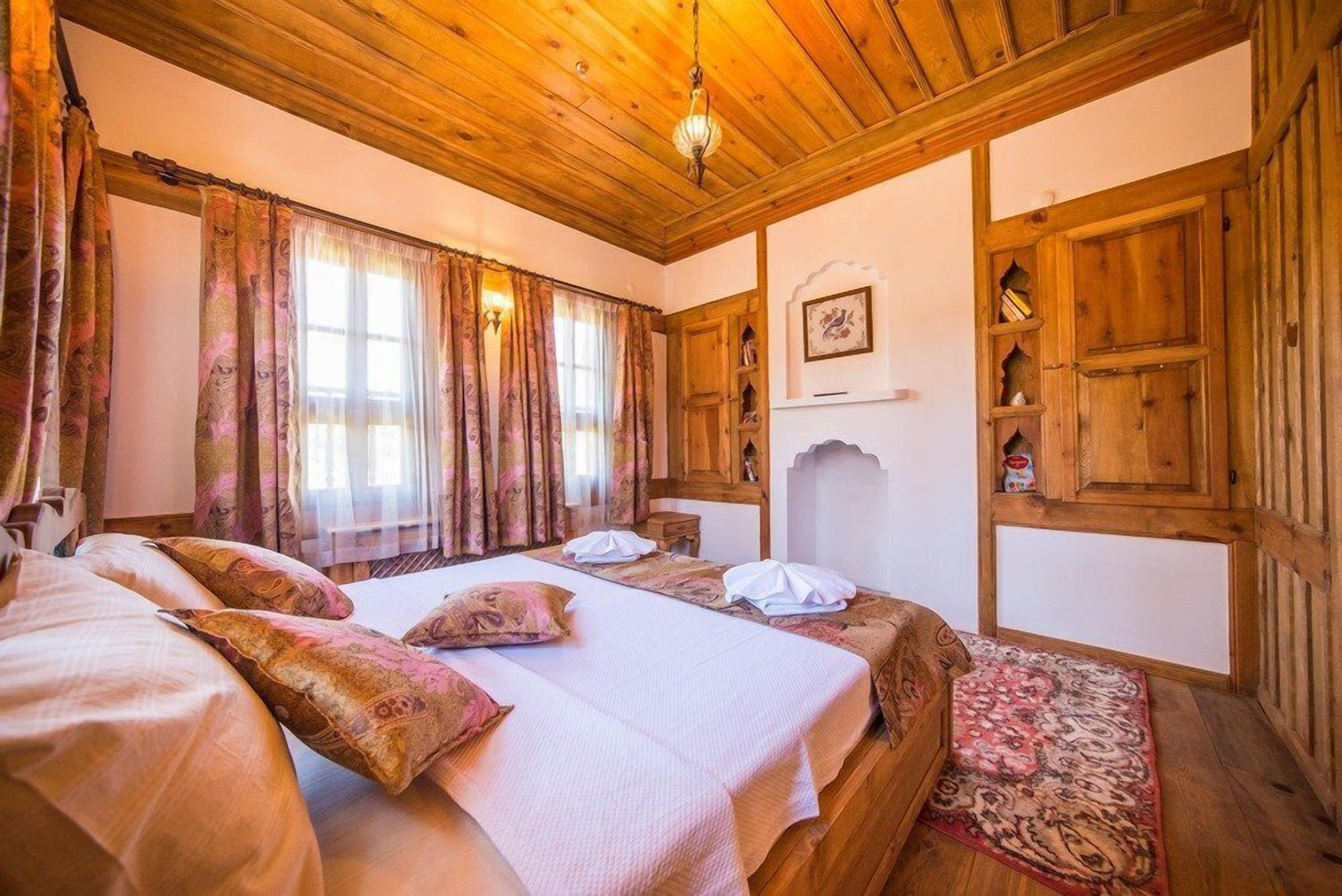 Una habitación tradicional de madera con una cama grande, dos mesitas de noche y un armario de madera.