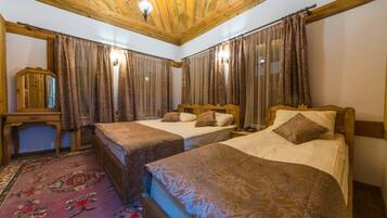 Ein Zimmer mit drei Betten, Holzboden und einem Blumenmuster-Teppich.