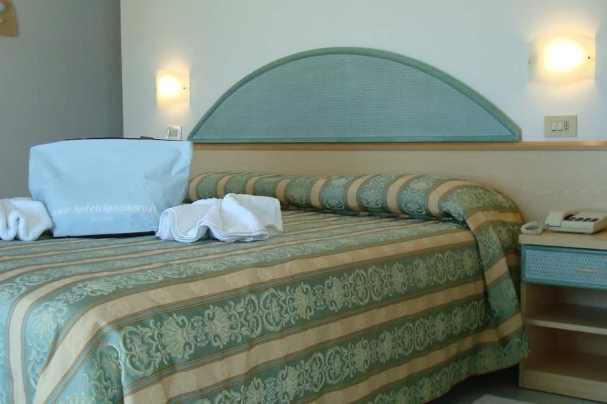A neatly made bed with a striped bedspread, a bedside table with a lamp, and a telephone.
