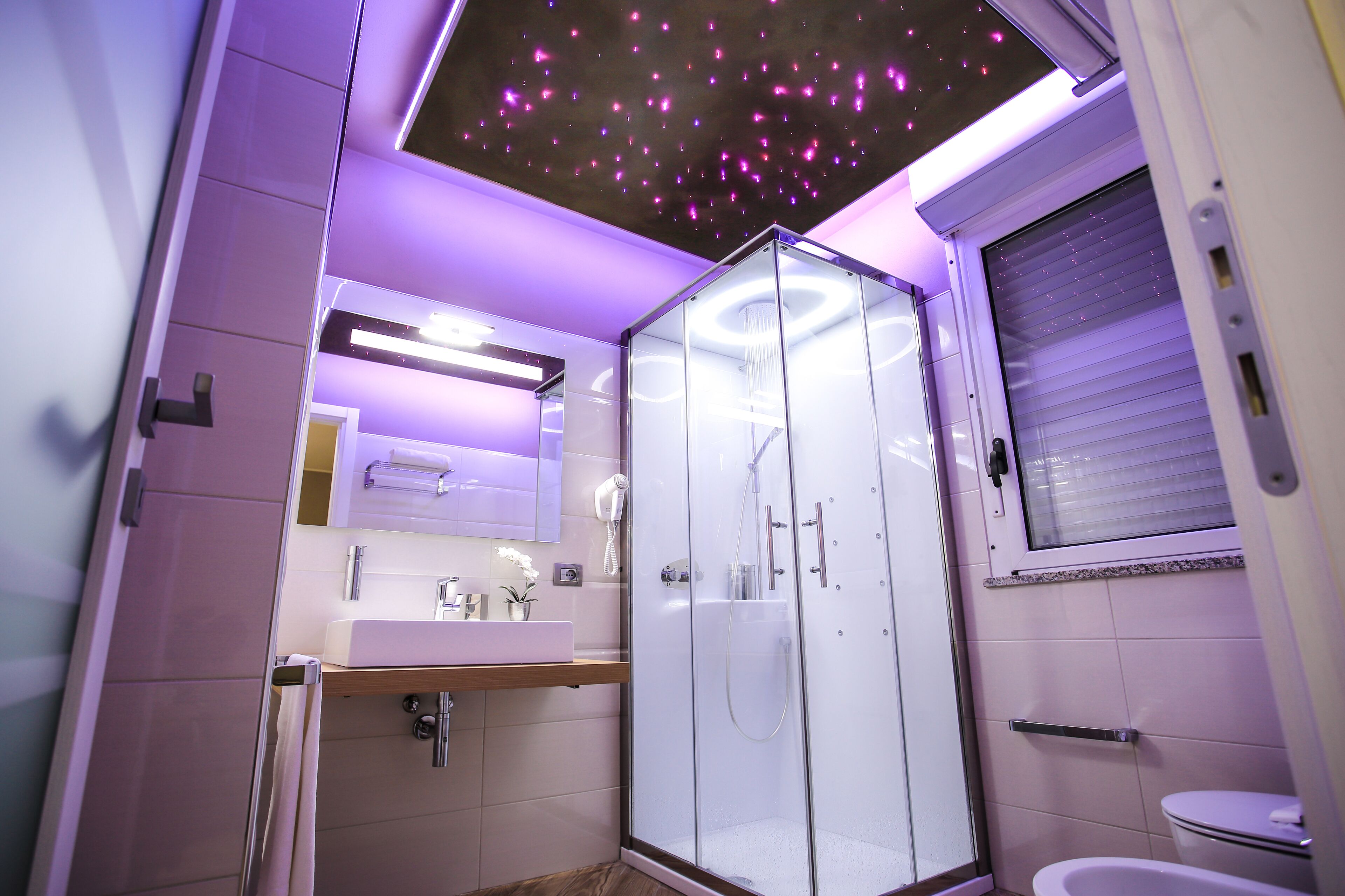 Un baño moderno con cabina de ducha de vidrio, tocador con espejo y un inodoro.