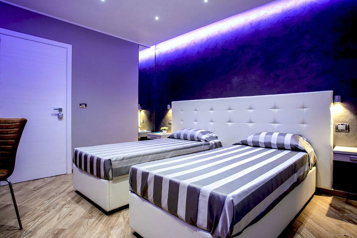 Un dormitorio moderno con dos camas individuales, una silla y una puerta.