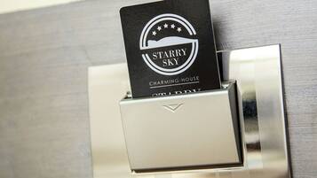 A metallic door handle with a black card inserted into a slot, displaying the logo and name "STARRY SKY CHARMING HOUSE".