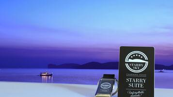 A smartwatch and a sign for the 'Starry Sky Charming House Starry Suite' with a view of a calm sea and distant mountains.