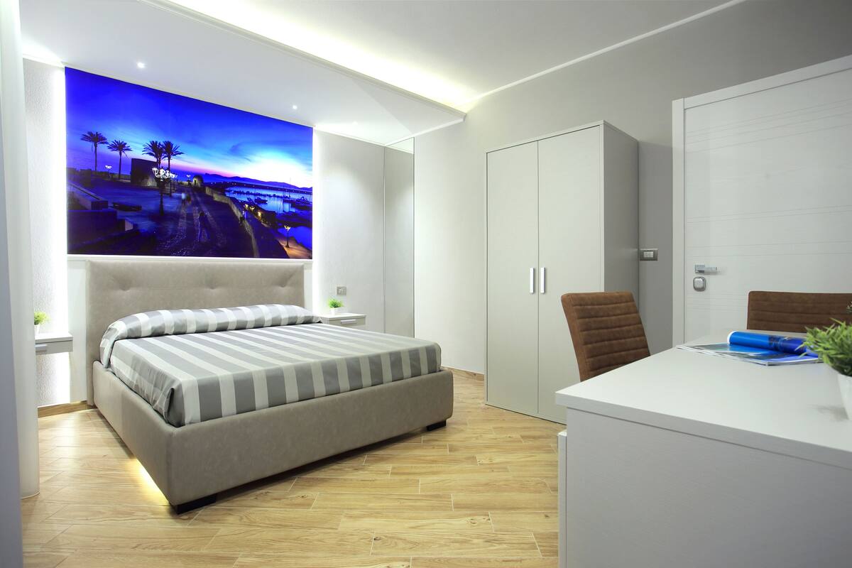 Un dormitorio moderno con una cama grande, un escritorio con una silla y un armario.