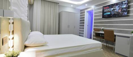 A modern bedroom with a bed, bedside table, and a TV mounted on the wall.