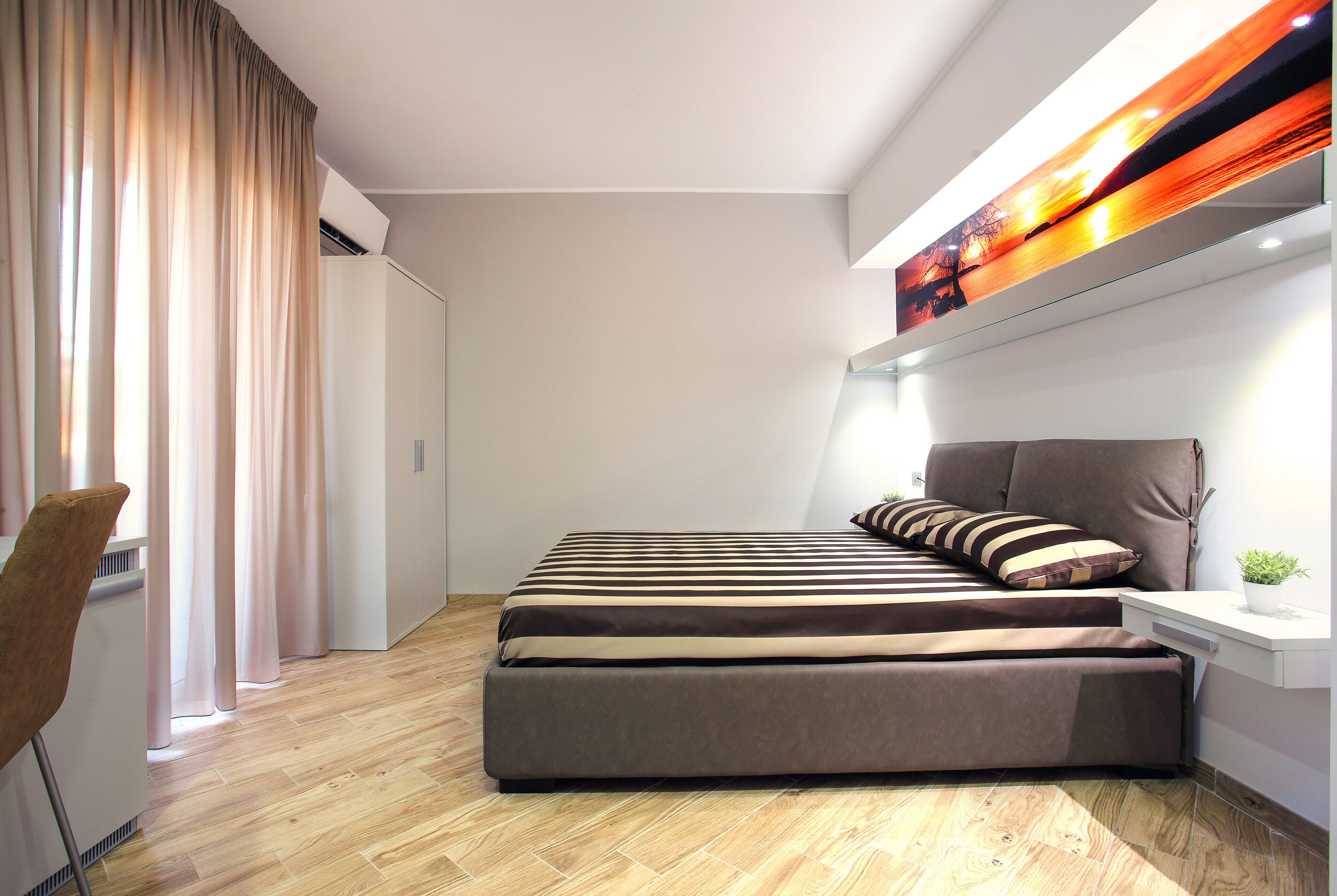 A modern bedroom with a bed, a chair, and a bedside table.
