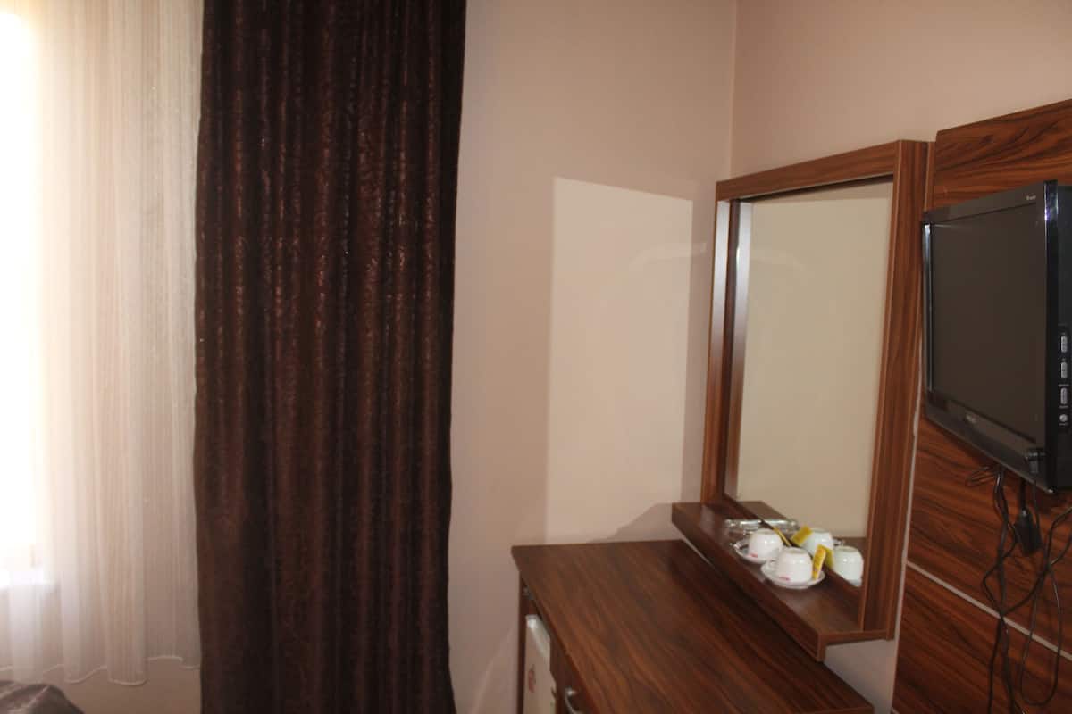Une chambre d’hôtel avec une commode en bois, un miroir et un téléviseur.