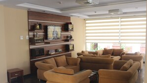 A spacious living area with multiple sofas and a built-in entertainment unit with shelves and a television. - Konya Hotel (Konya)