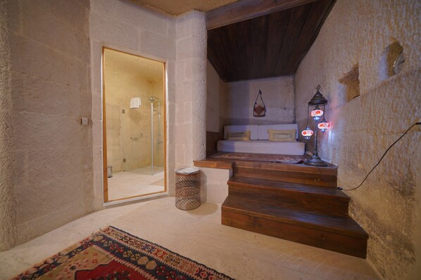 A staircase with wooden steps leading to a landing, a small round table, and a patterned rug on the floor. - Salkim Cave House (Nevsehir)