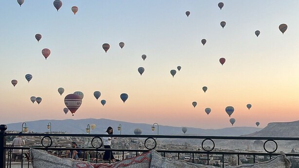 Un lit avec vue sur les montgolfières au coucher du soleil.