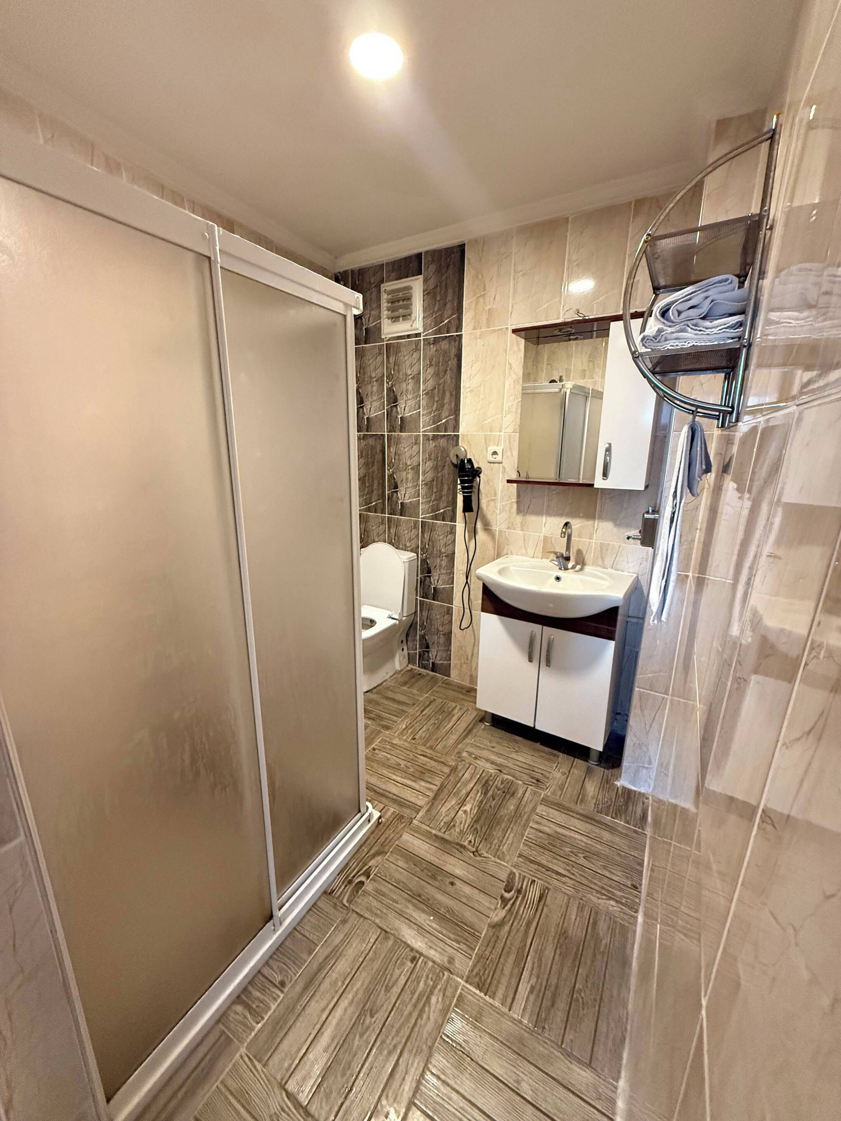 Un baño con ducha, inodoro, lavabo y perchero para toallas.