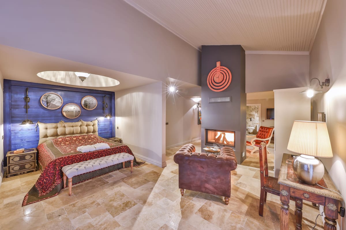A spacious bedroom with a large bed, a fireplace, and a seating area.