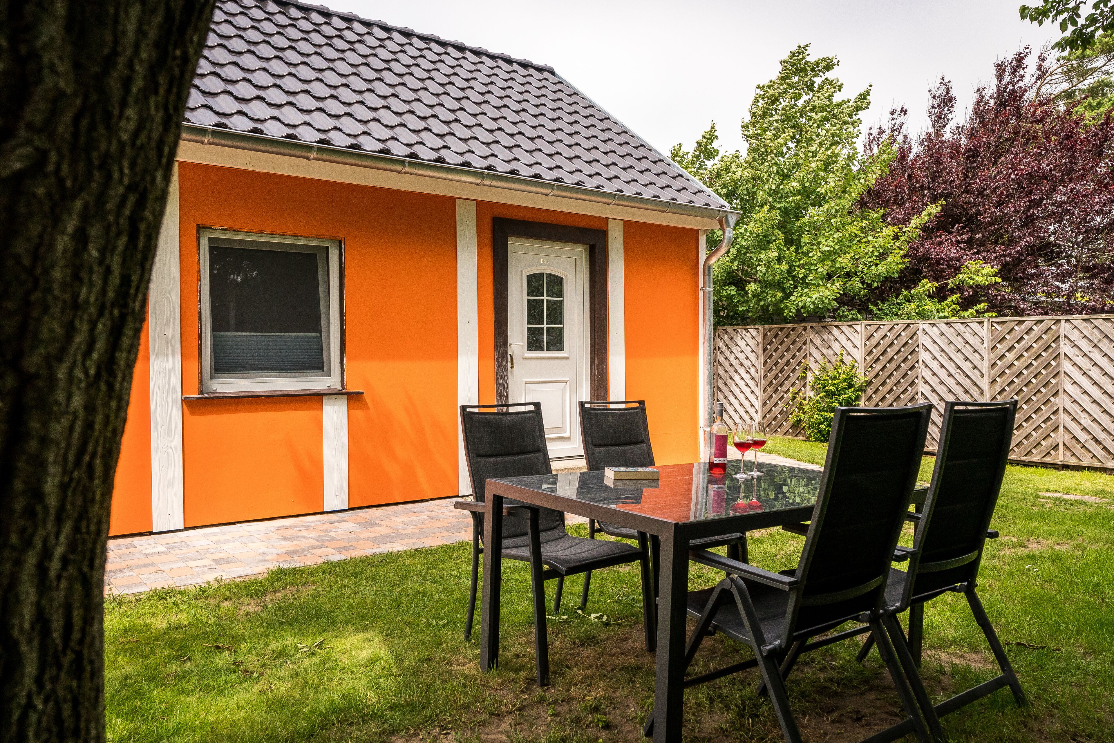 Una casa con techo de tejas, puerta principal y un pequeño patio con mesa y sillas.