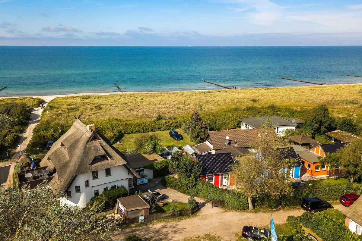A coastal residential area with houses, a beach, and a clear view of the sea.