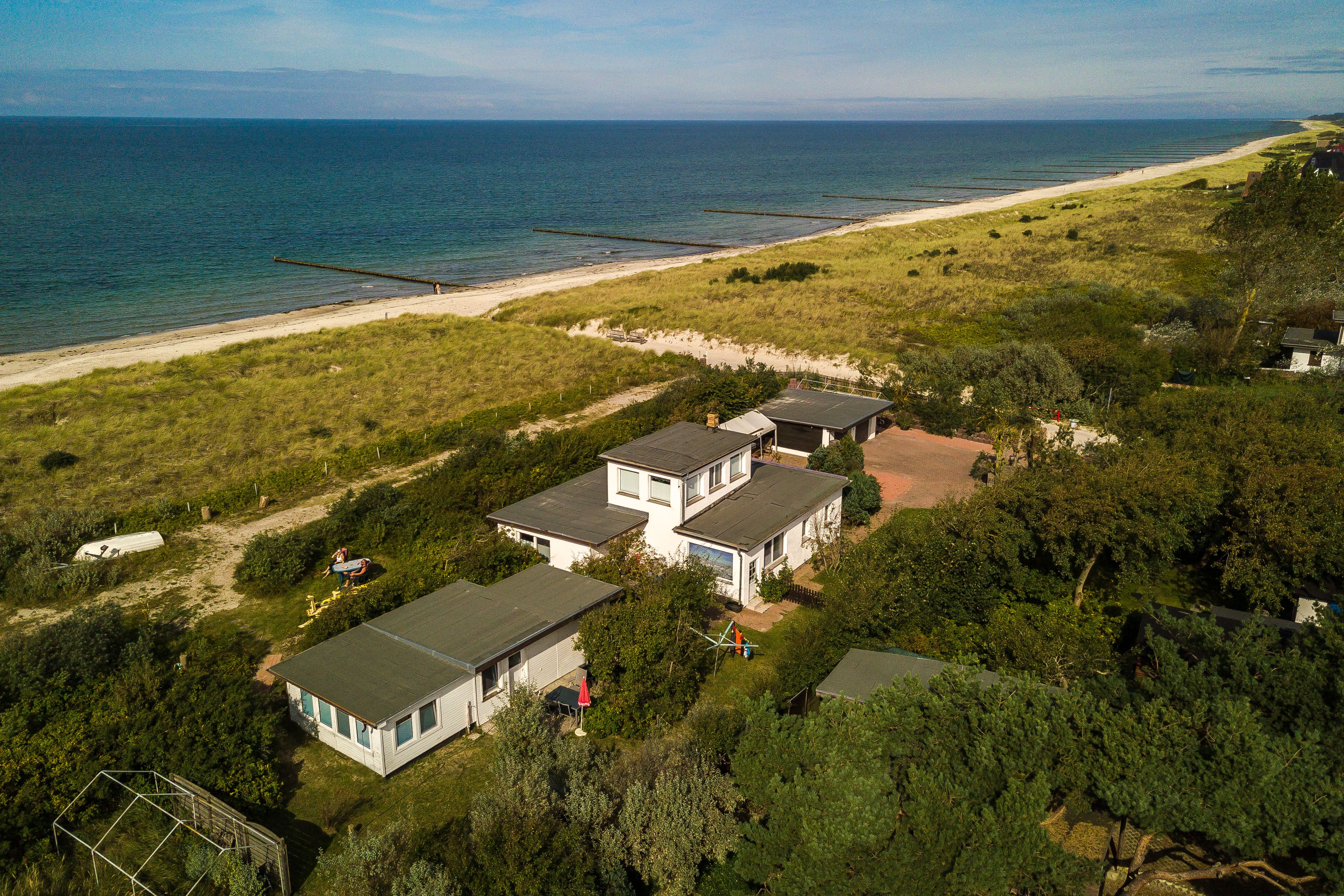 A coastal property with multiple detached houses, a beach, and a clear view of the ocean.