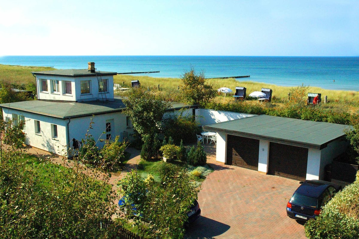 A coastal property with a two-story house, a garage, and a car parked in the driveway.