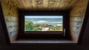 Vista a través de una ventana de una cabaña de madera con vista al océano.