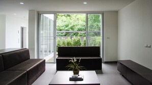 A modern living room with a sofa, a coffee table with a plant, and a large window offering a view of greenery. - Ozone Khaotao (Hua Hin)