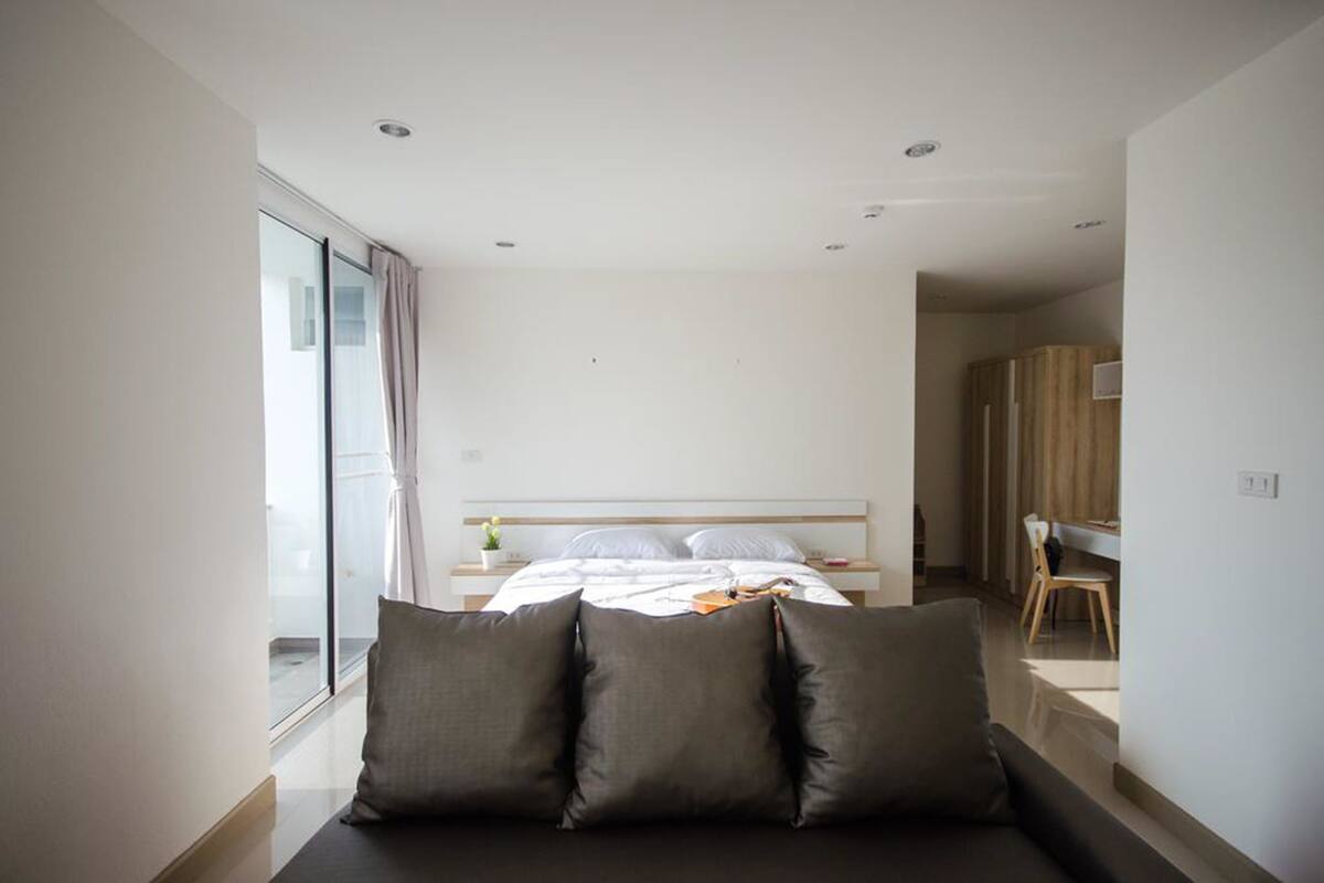 A modern bedroom with a bed, a sofa, and a desk.