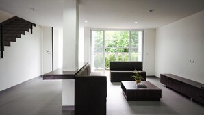 A modern interior with a staircase, a seating area, and large windows. - Ozone Khaotao (Hua Hin)