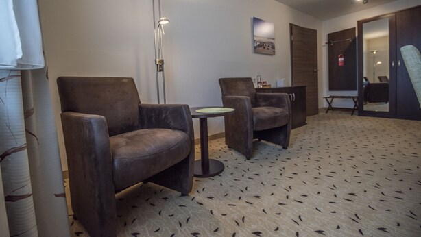 Une pièce moderne avec deux fauteuils en cuir, une petite table ronde, un lampadaire et un tapis à motifs.