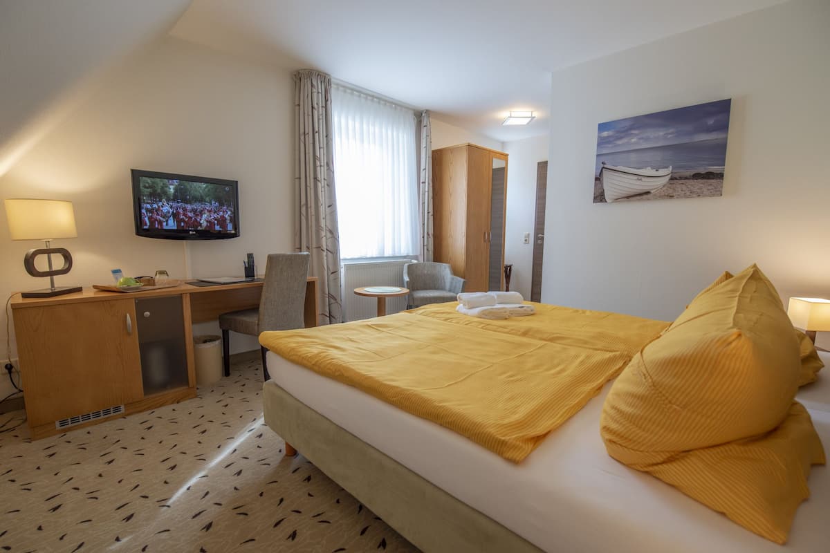 Une chambre d’hôtel avec un lit, un bureau, une télévision et une fenêtre avec des rideaux.